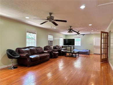 Living area featuring ornamental molding, wood-type flooring, ceiling fan, recessed lighting, and baseboards