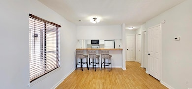Kitchen featuring a kitchen bar, light wood-style flooring, freestanding refrigerator, a peninsula, and black microwave