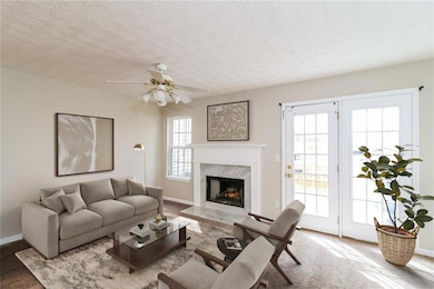 Carpeted living area with a premium fireplace, a ceiling fan, and a textured ceiling