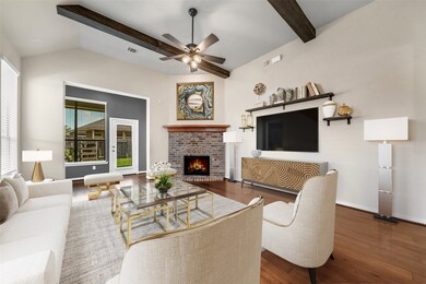 This living room is more like a GREAT room featuring a stunning fireplace with mantel detailing, custom paint, high ceiling with wood beam accent, dark stained ceiling fan with lighting, and large windows with privacy blinds.