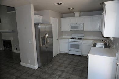 Kitchen with light countertops, white appliances, white cabinetry, and a fireplace