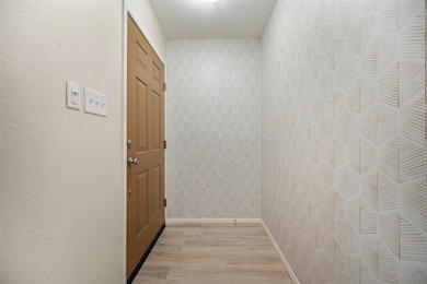 Hall with light wood-style flooring and baseboards