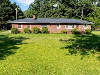 Ranch-style home featuring brick siding, a front lawn, and a chimney
