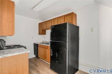 Kitchen with black appliances, light countertops, light wood-style floors, and brown cabinetry
