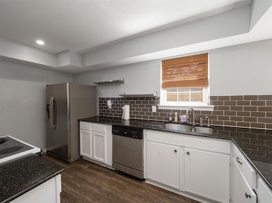 Kitchen featuring white cabinets, sink, backsplash