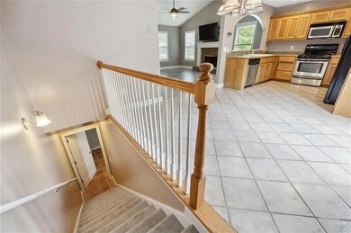 Staircase featuring a ceiling fan, tile patterned floors, a fireplace, and vaulted ceiling