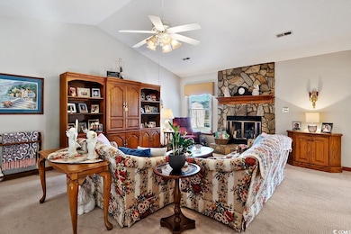 Living room with ceiling fan, light carpet, a ston