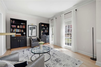 Living area with crown molding, baseboards, and li
