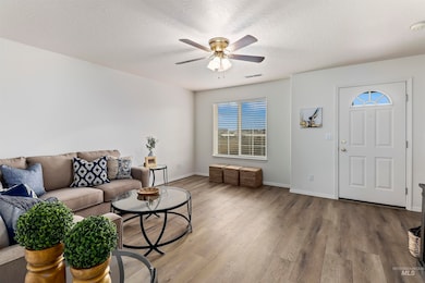 Living room with wood finished floors, ceiling fan, and a textured ceiling