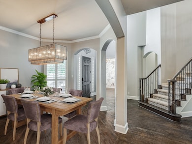 Dining space with crown molding, dark wood-type flooring, stairs, and arched walkways