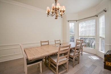 Large and bright dining room features elegant wainscoting, crown molding and beautiful bamboo floors.