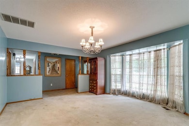 Unfurnished room with a chandelier, carpet floors, baseboards, and a textured ceiling