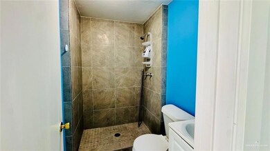 Bathroom featuring tiled shower, toilet, and vanity