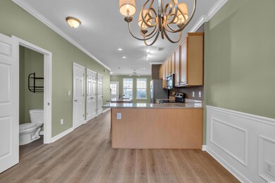 Kitchen with appliances with stainless steel finishes, crown molding, a chandelier, a peninsula, and light wood-style flooring