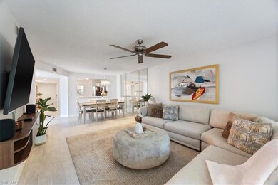 Living room with ceiling fan, light wood-style flooring, a chandelier, and a textured ceiling