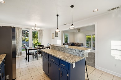 Kitchen featuring light stone countertops, light tile patterned flooring, decorative light fixtures, freestanding refrigerator, and blue cabinets