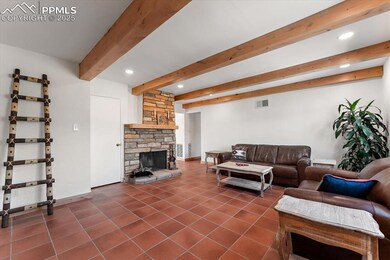 Living area featuring beamed ceiling, terra cotta tile flooring, a wet bar, and a fireplace