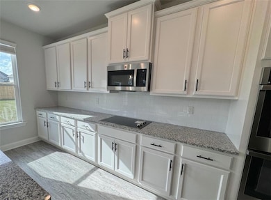 Kitchen featuring white cabinets, light wood-type 