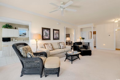 Living area with crown molding, baseboards, ceiling fan, light colored carpet, and light tile patterned flooring