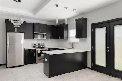 Kitchen featuring appliances with stainless steel finishes, tasteful backsplash, light countertops, and light marble finish floors