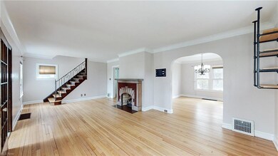 Living room with crown molding, built in shelves, a fireplace, and light hardwood flooring