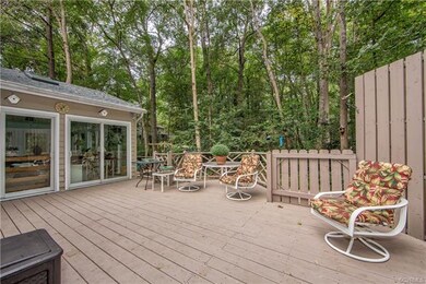 View of rear sun room opening onto part of the wrap around deck with privacy wall.