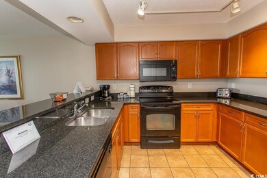 Kitchen featuring black appliances, dark stone cou