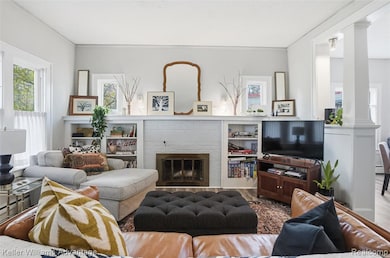 Living area featuring wood finished floors, a brick fireplace, and ornamental molding