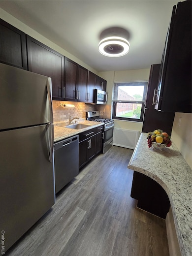 Kitchen featuring fridge, stainless steel range with gas cooktop, dishwashing machine, dark wood-type flooring, and tasteful backsplash