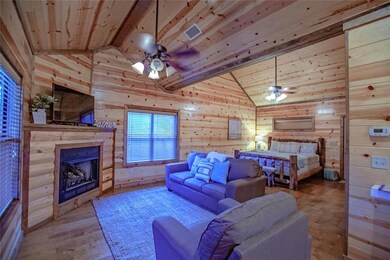 Bedroom with wood walls, wood finished floors, a fireplace, a wood ceiling with exposed beams, and high vaulted ceiling