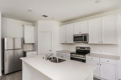 Kitchen with sink, a center island with sink, white cabinetry, appliances with stainless steel finishes, and light wood-type flooring