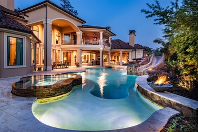 The outstanding swimming pool boasts a hot tub, oversized tanning shelf, a slide, a waterfall flanked by fire pits, beach entry, all surrounded by travertine pavers and impressive stonework.