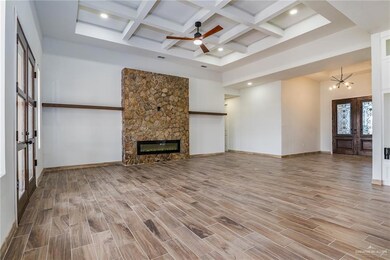 Unfurnished living room with ceiling fan with notable chandelier, french doors, a high ceiling, and a fireplace