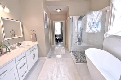 Full bath featuring a stall shower, vanity, a freestanding bath, and crown molding
