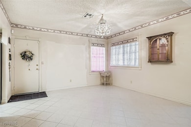 Entryway featuring a textured ceiling, a chandelier, and light tile patterned floors