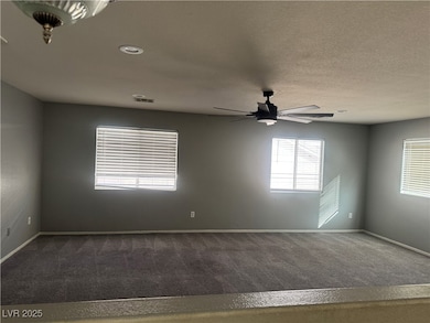 Unfurnished room featuring dark carpet, a textured ceiling, and a ceiling fan