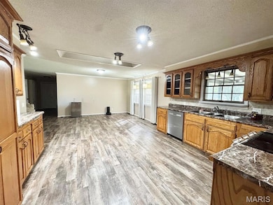 Kitchen with a textured ceiling, plenty of natural light, light wood-style flooring, and dark stone countertops