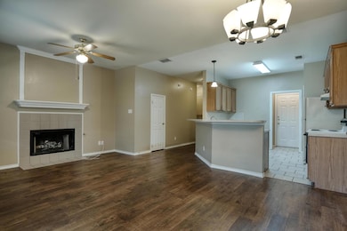 Kitchen featuring open floor plan, dark wood-style flooring, light countertops, a ceiling fan, and brown cabinetry