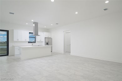 Kitchen with white cabinetry, island exhaust hood,