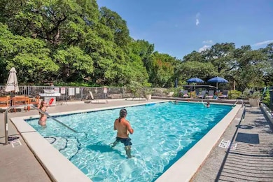 Community pool with view of wooded area and a pat