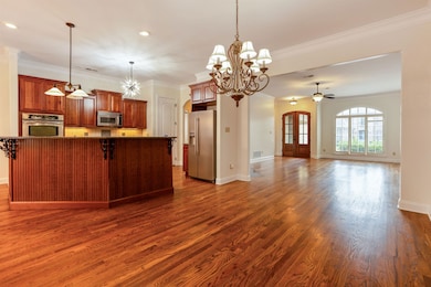 Kitchen with appliances with stainless steel finishes, dark wood-style flooring, crown molding, open floor plan, and a ceiling fan