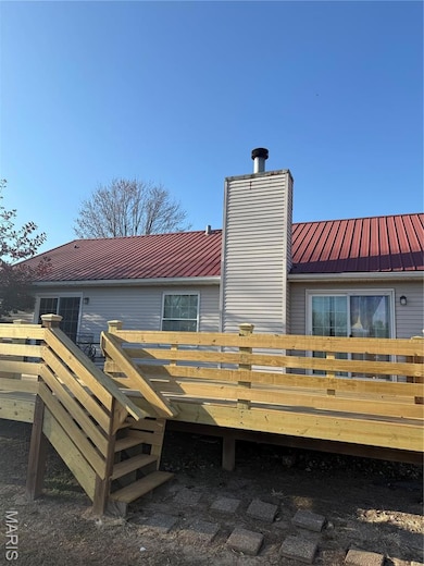 Rear view of house featuring a metal roof, a deck, and a chimney