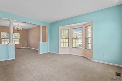 Spare room with decorative columns, an inviting chandelier, a healthy amount of sunlight, and carpet flooring