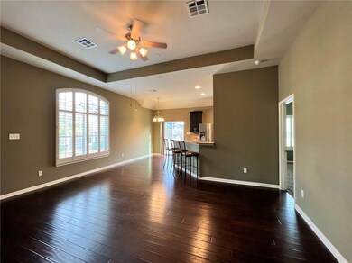 Unfurnished living room featuring a ceiling fan, dark wood finished floors, a chandelier, a raised ceiling, and recessed lighting