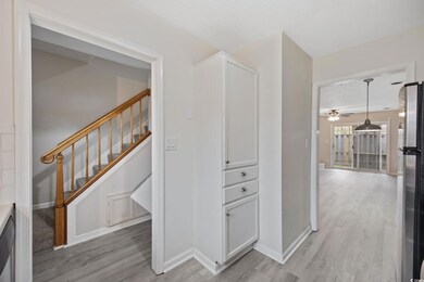 Hall featuring baseboards, a textured ceiling, stairway, and light wood-type flooring