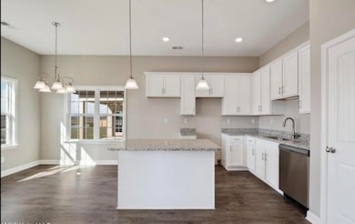 Kitchen with dishwasher, a kitchen island, dark wood-style floors, white cabinetry, and recessed lighting
