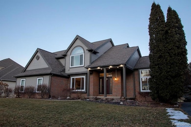 View of front of property featuring brick siding, a front yard, and roof with shingles