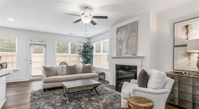 Living room featuring a ceiling fan, dark wood-style floors, a glass covered fireplace, baseboards, and recessed lighting