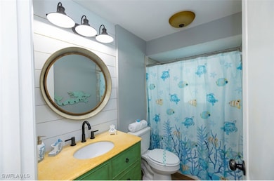 Bathroom featuring toilet, vanity, wood walls, and