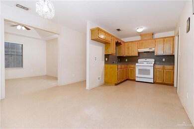 Kitchen featuring white range oven, light tile flooring, tasteful backsplash, and ceiling fan with notable chandelier